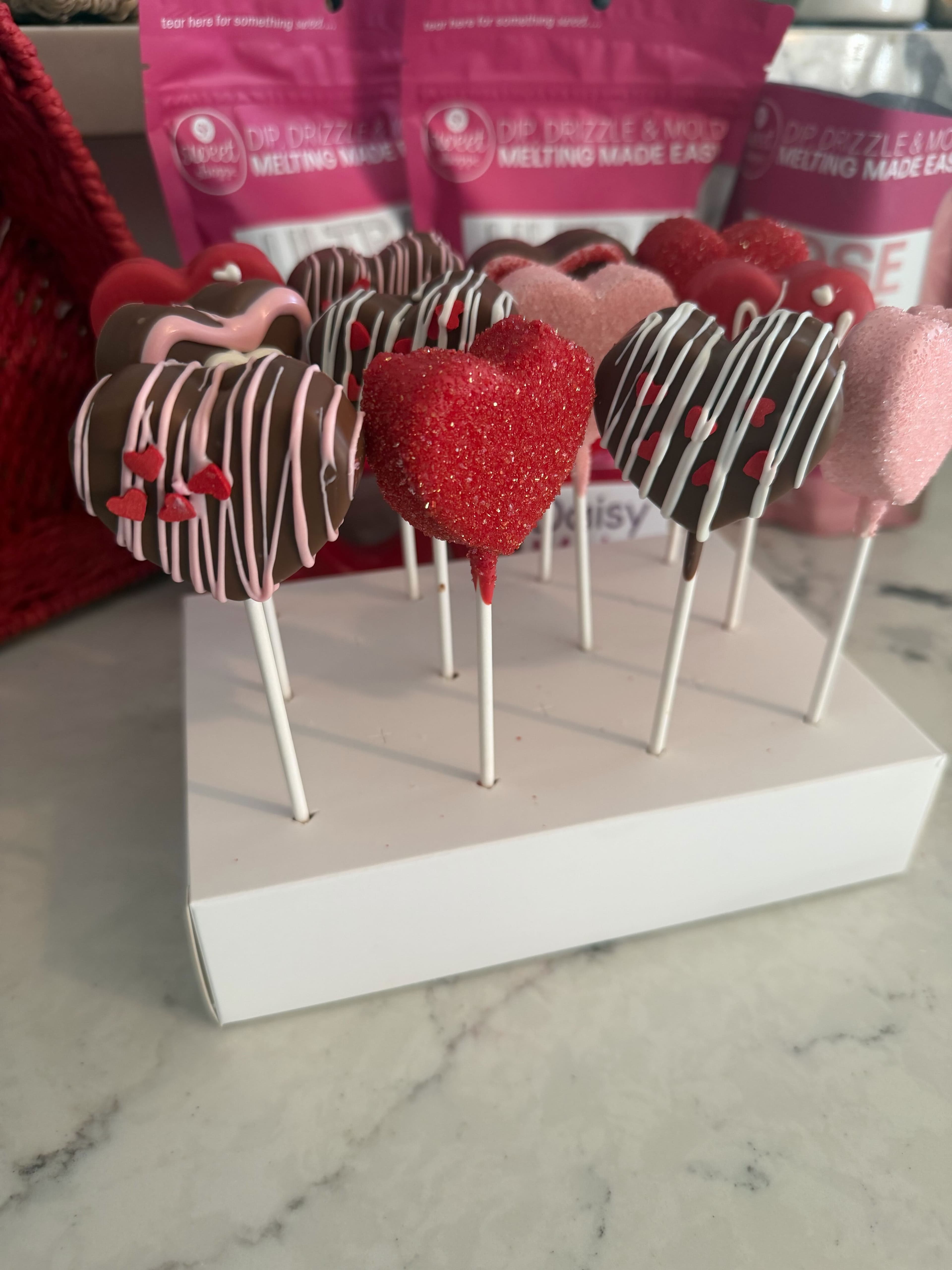 Heart-shaped Valentine cake pops with chocolate, pink coatings, and sprinkles