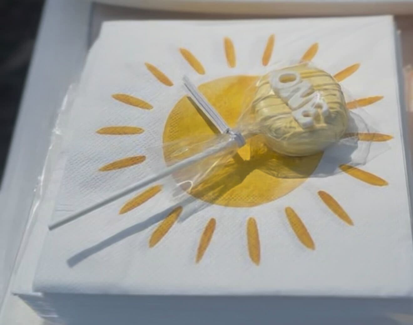 Yellow "ONE" first birthday cake pop on a sunshine napkin